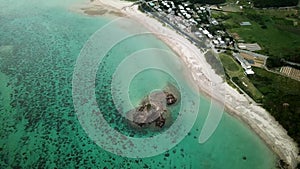 Aerial footage of Kayo Beach with huge rock and turquoise water in Okinawa.