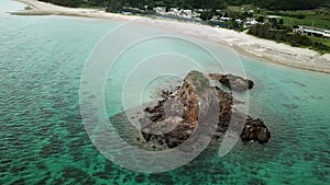 Aerial footage of Kayo Beach with huge rock and turquoise water in Okinawa.