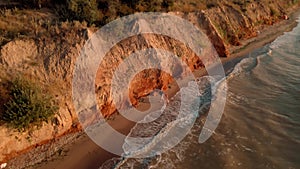 aerial footage of men running at early morning outdoor along sea shore under clay canyon on sea coast. active leisure