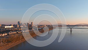 Aerial footage of the Mississippi river at sunset with a bridge over the water and skyscrapers and office buildings