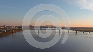 Aerial footage of the Mississippi river at sunset with a bridge over the water and skyscrapers and office buildings