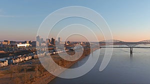 Aerial footage of the Mississippi river at sunset with a bridge over the water and skyscrapers and office buildings