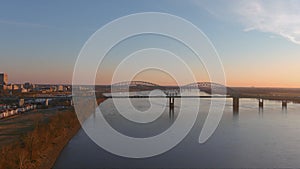 Aerial footage of the Mississippi river at sunset with a bridge over the water and skyscrapers and office buildings