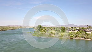 Aerial footage of the silky green waters of the Colorado River with people riding jet skis and lush green trees and plants