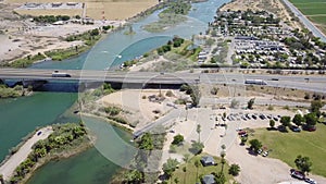 Aerial footage of the silky green waters of the Colorado river with people riding jet skis and sailing boats and a street