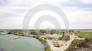 Aerial footage of the silky green waters of the Colorado river with people riding jet skis and sailing boats and a street with car