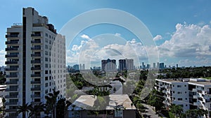 aerial footage of skyscrapers, hotels and apartments in the city skyline, cars on the street lush green palm trees and grass