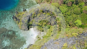 Aerial footage of small beach near big lagoon with lonely banca local boat on paradise sandy beach. Miniloc island El