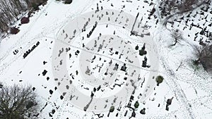 Aerial footage of a snowy day in the city of Leeds in the UK showing a snow filled grave yard cemetery with bar trees and snow