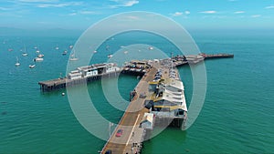 aerial footage of Stearns Wharf Pier with blue ocean water, boats and yachts sailing and people walking and cars driving