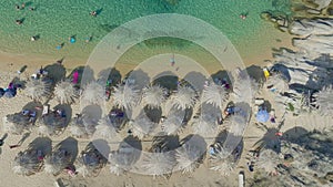 Aerial footage of sunbathers and umbrellas on clear beachfront