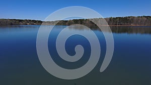 Aerial footage of the vast rippling blue waters of the lake surrounded by lush green trees and plants