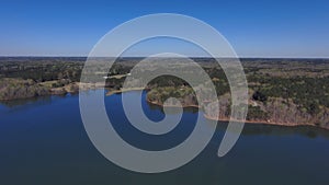 Aerial footage of the vast rippling blue waters of the lake surrounded by lush green trees and plants