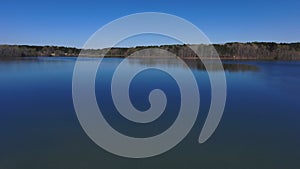 Aerial footage of the vast rippling blue waters of the lake surrounded by lush green trees and plants