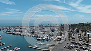 aerial footage of West Beach with boats and yachts docked in the marina, cars driving on the street surrounded by green trees