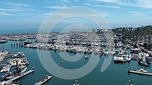 aerial footage of West Beach with boats and yachts docked in the marina, cars driving on the street surrounded by green trees