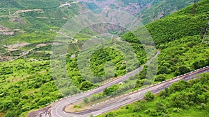 Aerial footage winding mountain road. Drone fly over  sharp turns in green mountains. Dangerous curves.