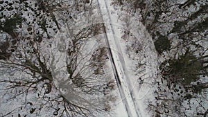 Aerial for the forest covered with snow and winter road, bird eye view. Shot. Top view of country road going through the