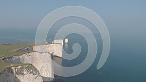 Aerial forward 4k footage along white cliff and crystal clear water toward Old Harry Rocks with a speed boat at full speed in the