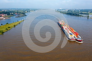 Aerial from a freighter full of containers cruising on the river Merwede near Gorinchem in the Netherlands in a flooded landscape