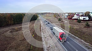 Aerial front side view of semi truck moving along a highway with cargo trailer.