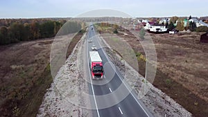 Aerial front side view of semi truck moving along a highway with cargo trailer.