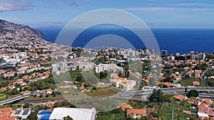 Aerial full view of the city of Funchal, urban buildings, atlantic ocean and Selvagens Islands as background, on Madeira Island,