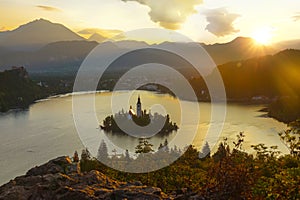 AERIAL: Golden evening sunbeams shine on the picturesque islet in lake Bled.