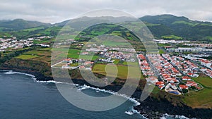 Aerial green cape landscape on cloudy day. Drone flight over dark ocean water