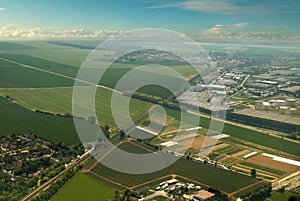 Aerial of green countryside & industrial city.