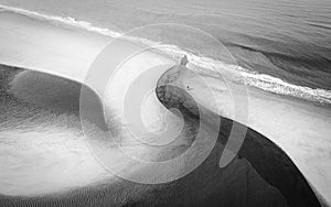 Aerial greyscale shot of a pathway on the beach near the waves of the ocean