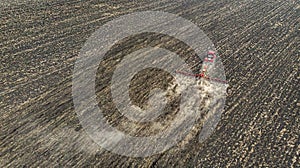 Aerial. Harvester plows the land in the field. Black earth soil cultivation. Top view