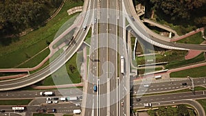 Aerial high drone flight over evening road traffic. Highway and overpass with cars and trucks, interchange, two-level road junctio