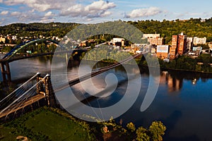 Aerial of Historic Wheeling Suspension Bridge + Downtown Buildings - Ohio River - Wheeling, West Virginia