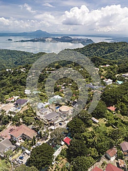 Aerial of houses along the Tagaytay caldera ridge with Taal volcano and lake further ahead in the background