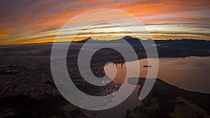 Aerial hyper-lapse of colorful sunrise clouds moving over lakeside Puerto Montt city in Chile