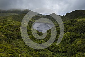 Aerial image of Lagoa Comprida caldera crater lake surrounded by green vegetation and with a stormy sky on the Ilha das Flores photo