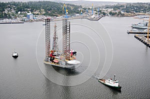 Aerial image of an oil drilling rig being towed out of port to a new location