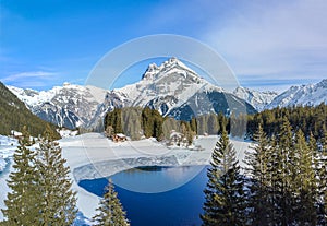 Aerial image of the winter landscape of the frozen Arni Lake with the snow-convered Alps peak Windgaellen