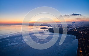 Aerial of industrial plant on the coast of a frozen Sea of Azov in Mariupol. Top view of the factory, smoke rising from