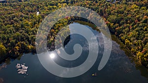 Aerial of a lake in upstate New York during the colorful fall foliage on a sunny day.