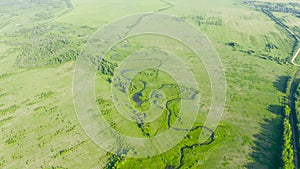 Aerial landscape countryside of winding small river, stream in green field, top view meadow