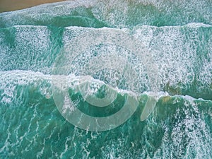 Aerial landscape looking down at crushing turquoise ocean waves.