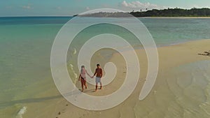 Aerial landscape of lovely travel couple relaxing on the white beach of tropical island in Philippines