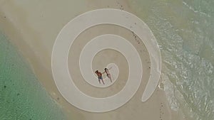 Aerial landscape of lovely travel couple relaxing on the white beach of tropical island in Philippines