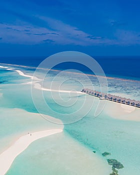 Aerial landscape, luxury tropical resort with water villas. Island beach, palm trees, sunny sky. Amazing bird eyes