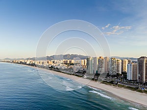 Aerial landscape photo of Barra da Tijuca beach , with waves crashing on beach during sunrise, with the beachfront