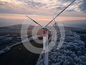 Aerial landscape photography of sunrise over frost-covered nature with wind turbines. Windmill in soft morning light