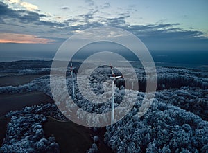 Aerial landscape photography of sunrise over frost-covered nature with wind turbines. Windmill in soft morning light