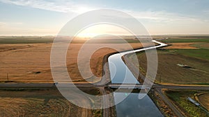 Aerial landscape of a river through a cultivated field at a dreamy sunrise